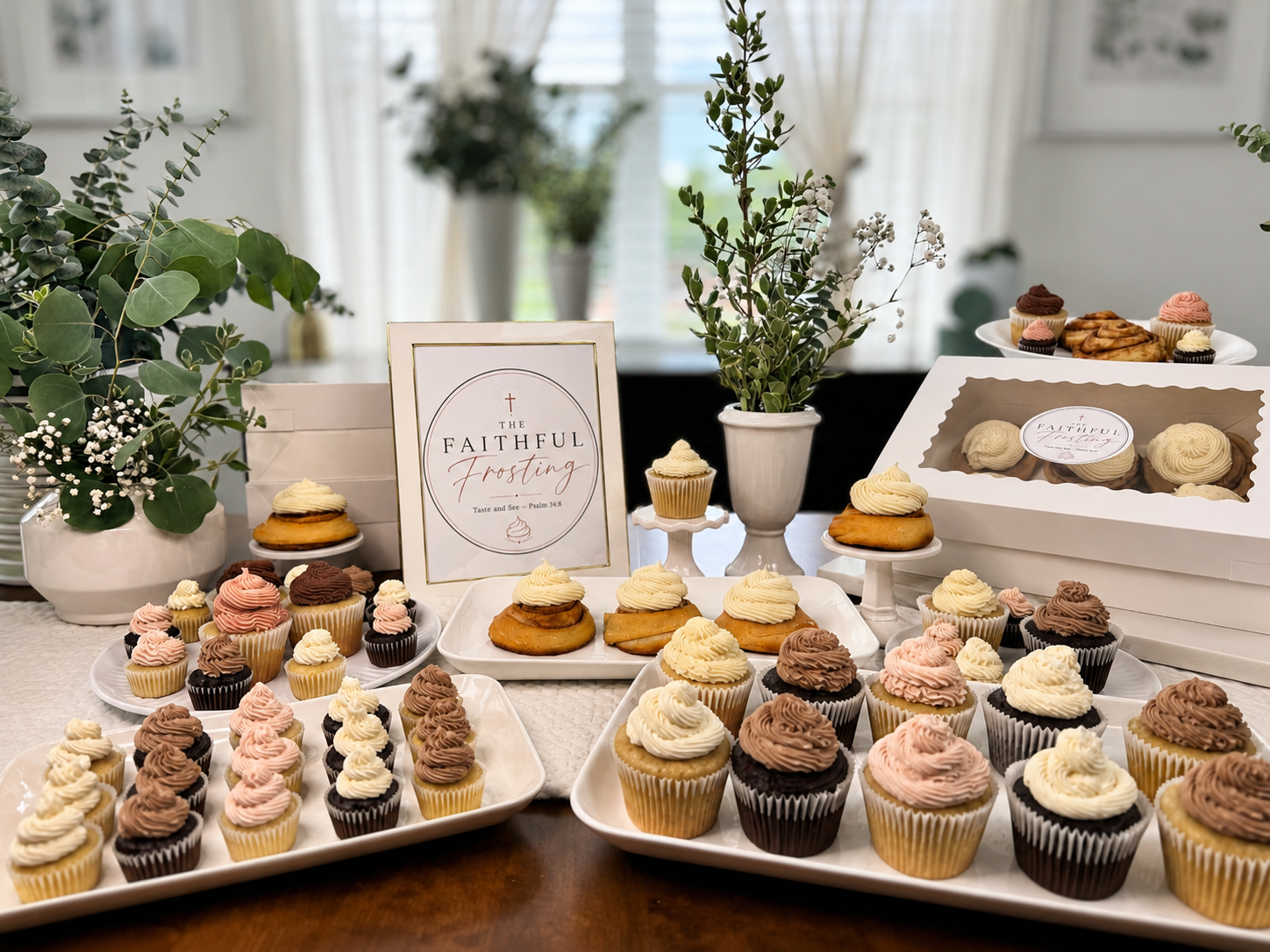 A display of sourdough cinnamon rolls and cupcakes on white serving plates